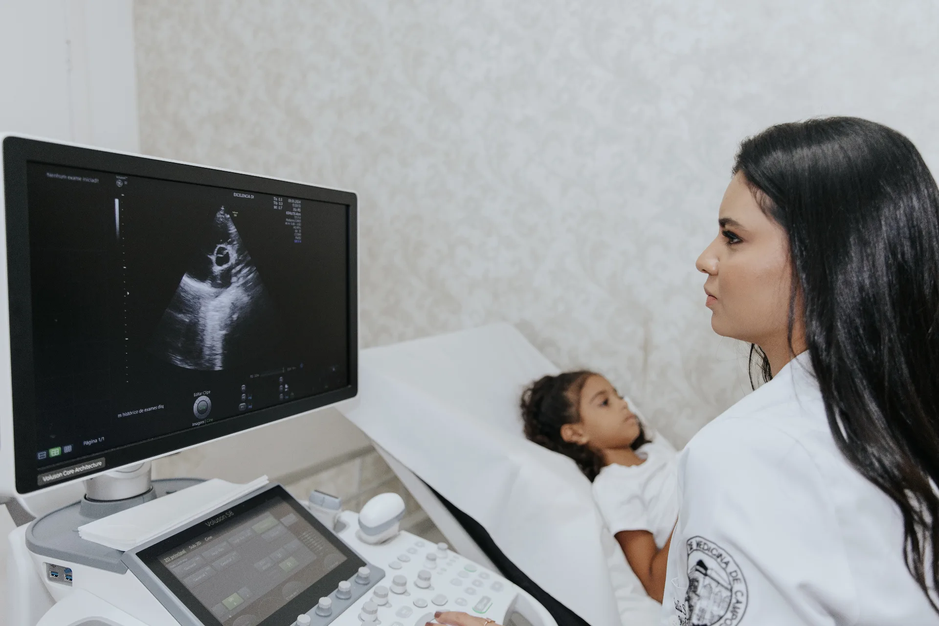 Dra. Rafaella Souza realizando ecocardiograma pediátrico em criança, com atenção e cuidado